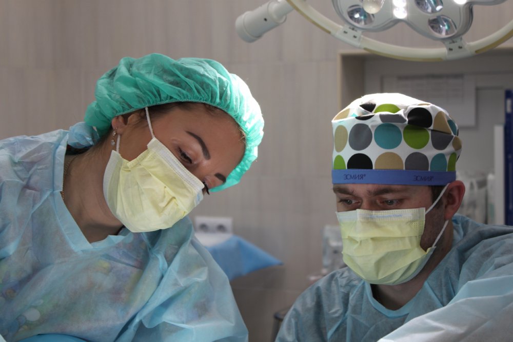 Surgeon and a male nurse performing liposuction